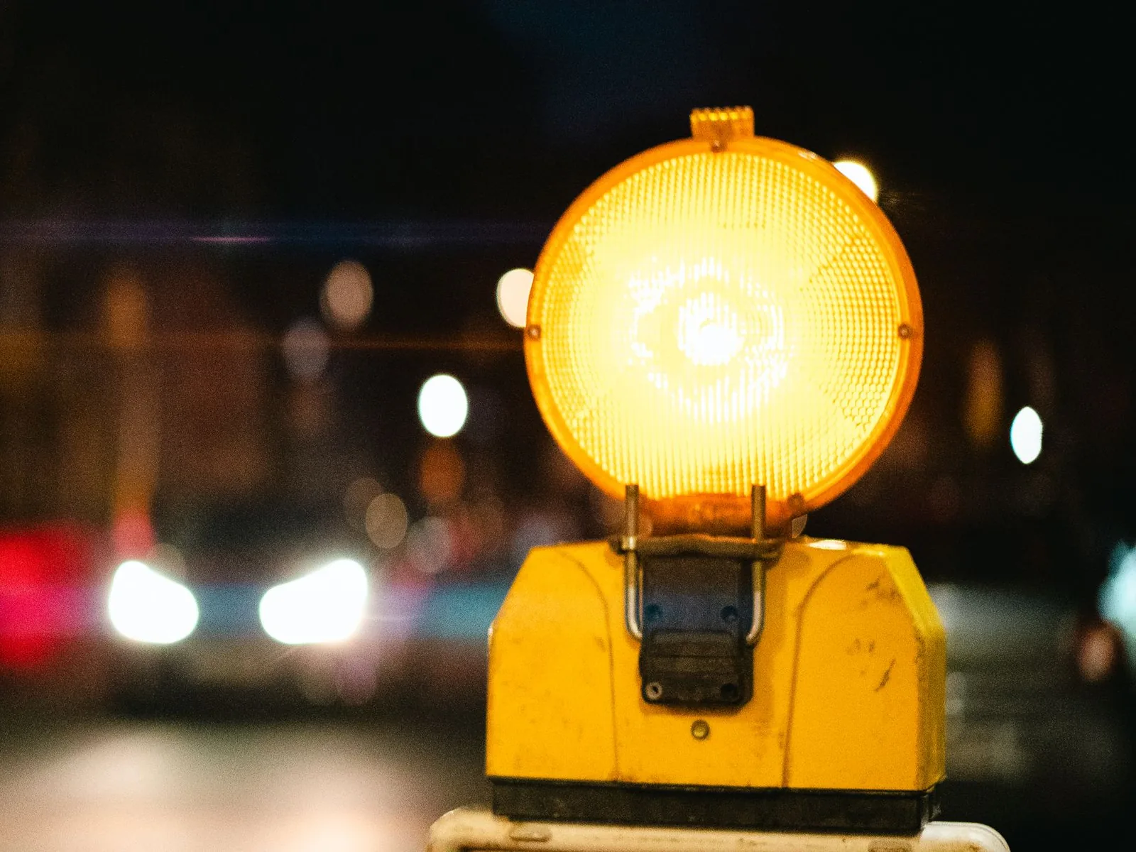 Una baliza lumínica ámbar encendida, de noche, junto a una calle