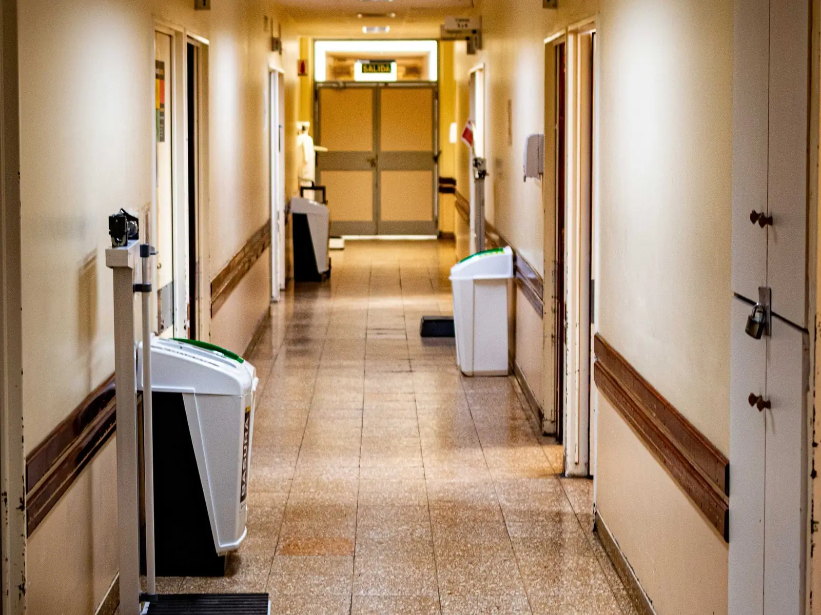 Pasillo de hospital vacío, con balanzas y papeleras junto a las paredes